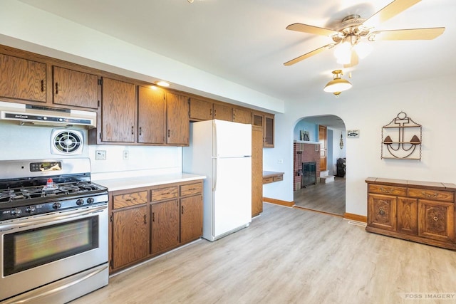 2894 Waubesa Ave, Madison, WI 53711 - kitchen with stainless steel gas stove, freestanding refrigerator, under cabinet range hood, arched walkways, and light wood-style floors