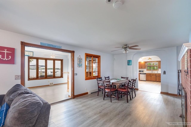 2894 Waubesa Ave, Madison, WI 53711 - dining area featuring arched walkways, light wood-style floors, ceiling fan, baseboard heating, and baseboards