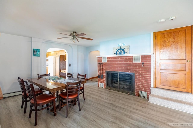 2894 Waubesa Ave, Madison, WI 53711 - dining area with arched walkways, light wood-style flooring, ceiling fan, a fireplace, and baseboard heating