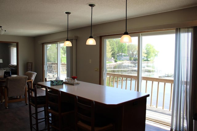 421 River St, Merrimac, WI 53561 - kitchen with a textured ceiling, a kitchen island, hanging light fixtures, light countertops, and a kitchen breakfast bar