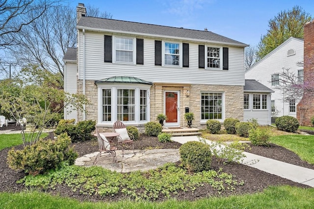 2522 Martha Ave, Green Bay, WI 54301 - view of front facade featuring stone siding, a chimney, a patio, and roof with shingles