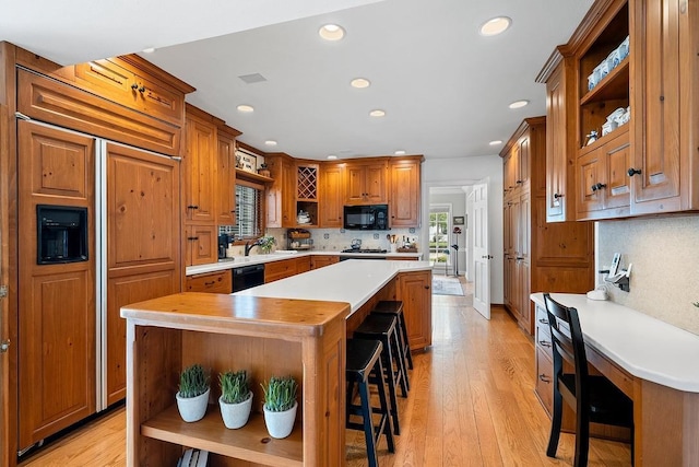 2522 Martha Ave, Green Bay, WI 54301 - kitchen featuring open shelves, black appliances, light countertops, a kitchen island, and a kitchen breakfast bar