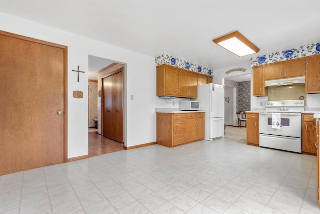 2009 N Eugene St, Appleton, WI 54914 - kitchen with white appliances, under cabinet range hood, light countertops, brown cabinetry, and light floors