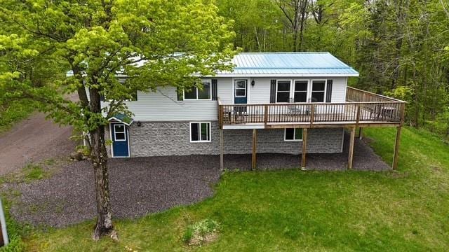 12757 County Highway T, Hayward, WI 54843 - rear view of property featuring a deck, a yard, a view of trees, metal roof, and stone siding