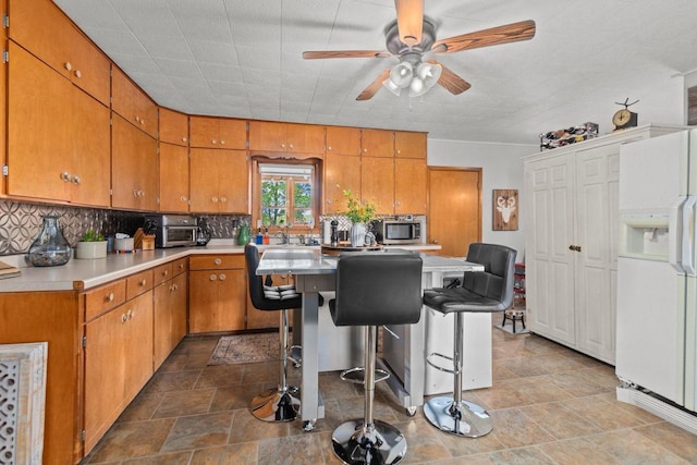 W13491 Reeds Corners Rd, Ripon, WI 54971 - kitchen with white fridge with ice dispenser, stainless steel microwave, tasteful backsplash, a ceiling fan, and brown cabinets