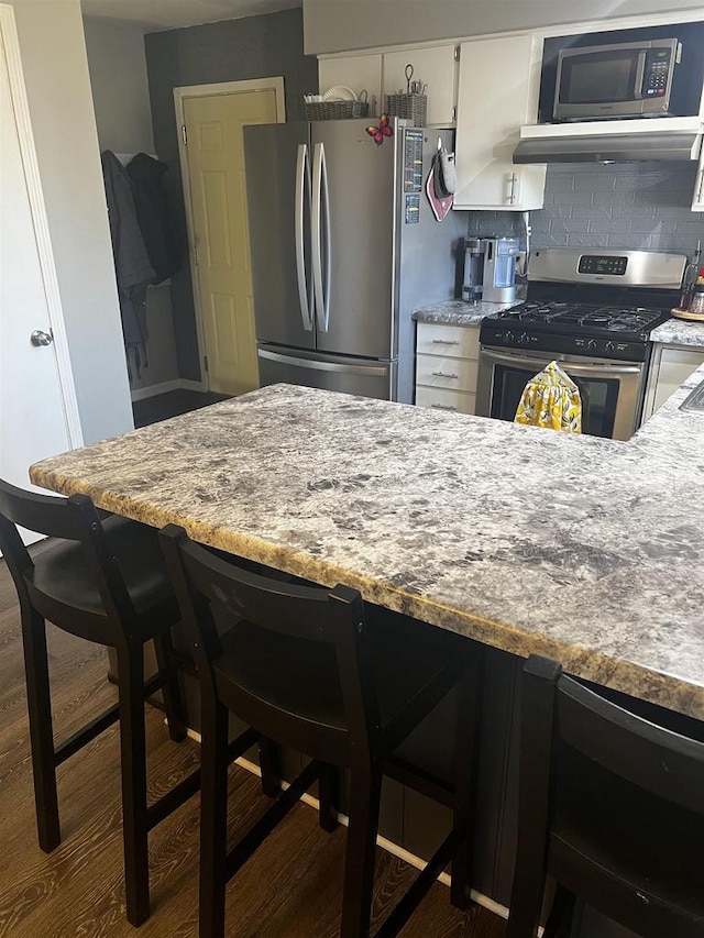 24 W Cottonwood Ln, Milton, WI 53563 - kitchen with stainless steel appliances, a kitchen bar, white cabinetry, and dark wood-style floors