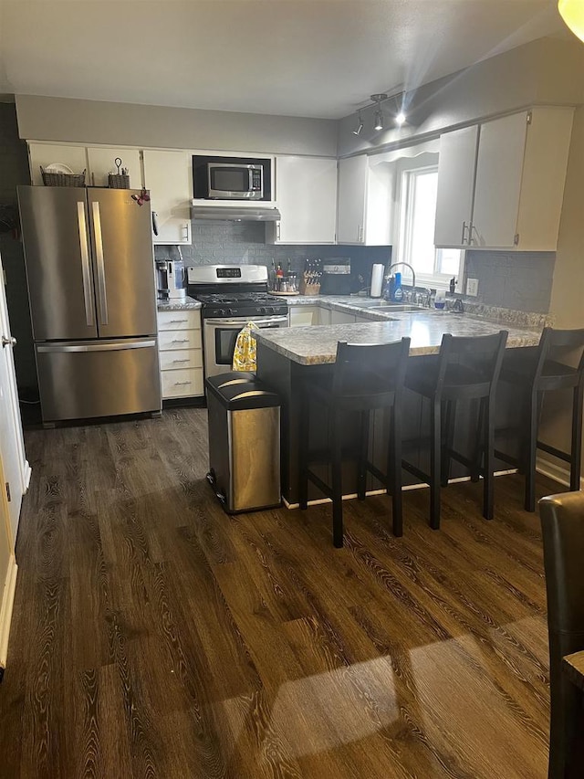 24 W Cottonwood Ln, Milton, WI 53563 - kitchen with appliances with stainless steel finishes, dark wood-style flooring, a peninsula, decorative backsplash, and white cabinets