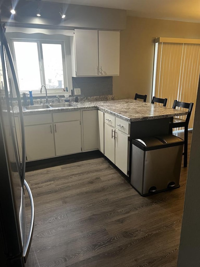 24 W Cottonwood Ln, Milton, WI 53563 - kitchen featuring a peninsula, freestanding refrigerator, dark wood-type flooring, white cabinets, and a sink