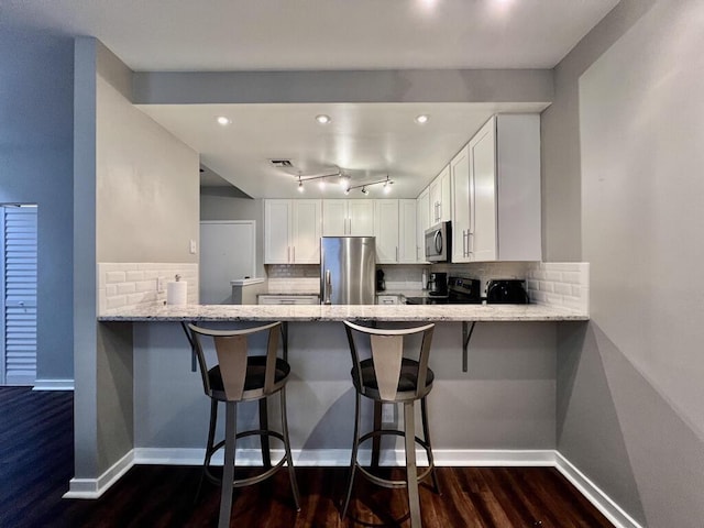 234 N Broadway Unit 302, Milwaukee, WI 53202 - kitchen featuring appliances with stainless steel finishes, dark wood finished floors, a peninsula, and light stone countertops