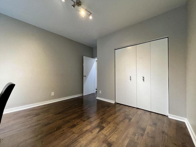 234 N Broadway Unit 302, Milwaukee, WI 53202 - unfurnished bedroom with dark wood-style flooring, baseboards, a closet, and track lighting