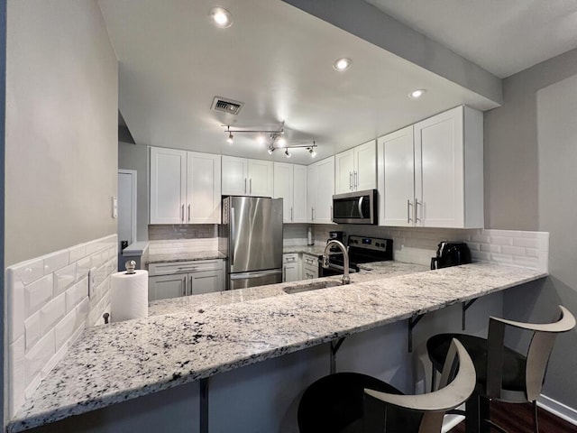 234 N Broadway Unit 302, Milwaukee, WI 53202 - kitchen with stainless steel appliances, light stone counters, decorative backsplash, a sink, and a peninsula