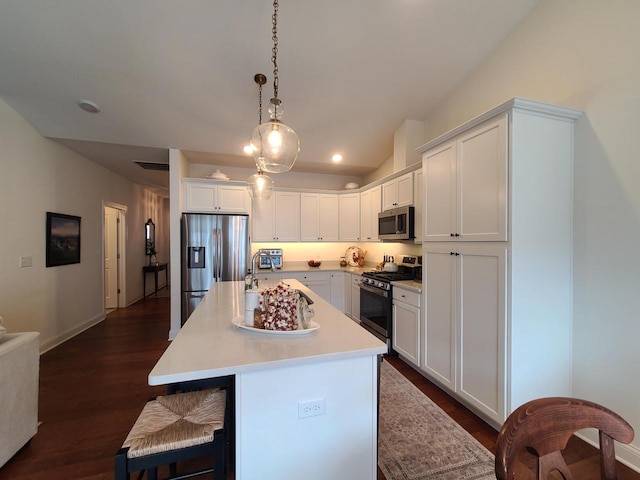 609 Cadence Cir, Lake Geneva, WI 53147 - kitchen featuring appliances with stainless steel finishes, white cabinets, a kitchen bar, light countertops, and dark wood finished floors