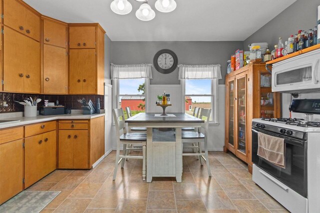 W13549 Reeds Corners Rd, Ripon, WI 54971 - kitchen with range with gas cooktop, white microwave, light countertops, backsplash, and a chandelier