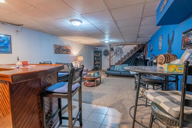 205 W Hickory St, Abbotsford, WI 54405 - carpeted living room featuring stairway, a bar, tile patterned floors, and a paneled ceiling