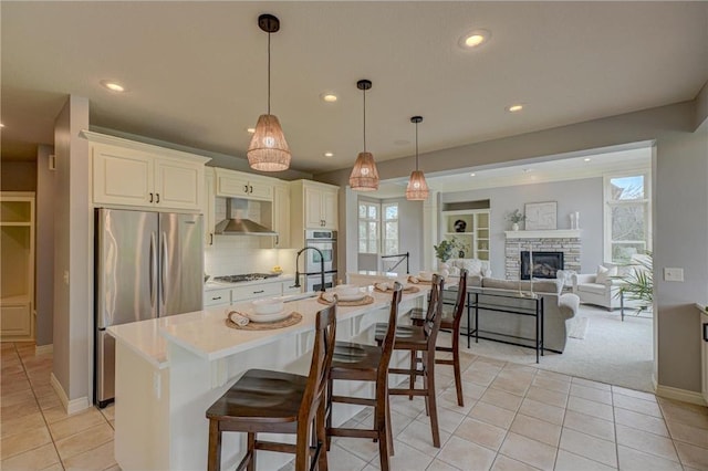 278 Saint Annes Pkwy, Hudson, WI 54016 - kitchen featuring appliances with stainless steel finishes, wall chimney range hood, recessed lighting, light tile patterned floors, and healthy amount of natural light