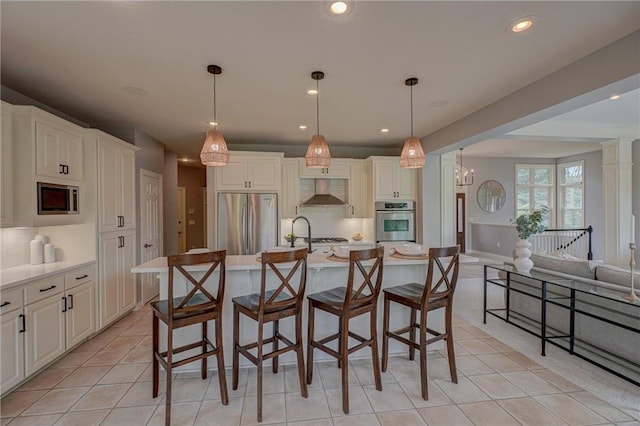 278 Saint Annes Pkwy, Hudson, WI 54016 - kitchen featuring appliances with stainless steel finishes, wall chimney exhaust hood, decorative backsplash, a kitchen breakfast bar, and recessed lighting