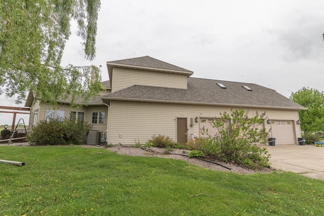 315 N 7th St, Colby, WI 54421 - rear view of property featuring driveway, an attached garage, a yard, central air condition unit, and roof with shingles