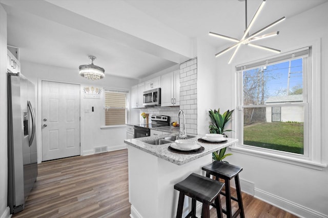 4193 N 19th Pl, Milwaukee, WI 53209 - kitchen with appliances with stainless steel finishes, a sink, baseboards, dark wood-style flooring, and white cabinets