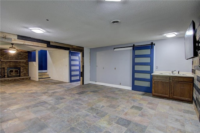 8054 223rd St, Cadott, WI 54727 - unfurnished living room with a barn door, a textured ceiling, a sink, a brick fireplace, and stone finish flooring