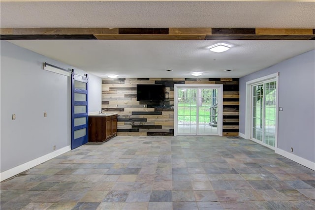 8054 223rd St, Cadott, WI 54727 - unfurnished living room featuring a barn door, baseboards, a textured ceiling, beam ceiling, and light stone finish floors