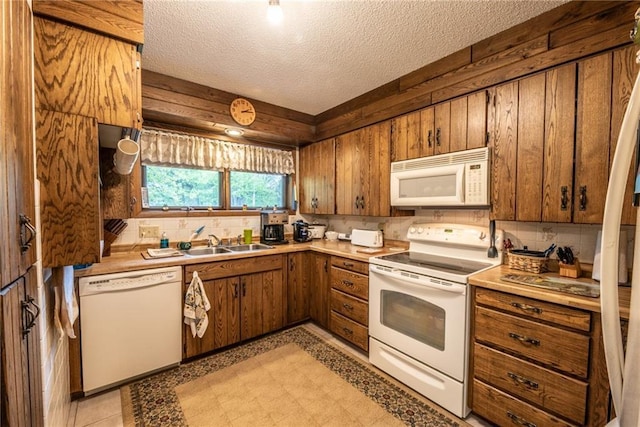 10790 Beal Ave, Hayward, WI 54843 - kitchen with white appliances, a sink, brown cabinetry, a textured ceiling, and decorative backsplash