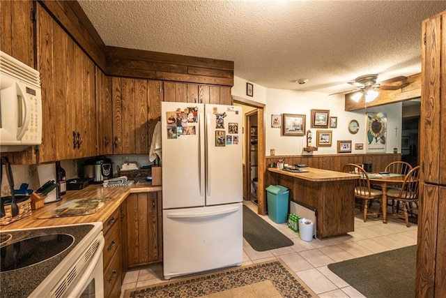 10790 Beal Ave, Hayward, WI 54843 - kitchen featuring white appliances, wood walls, a wainscoted wall, light tile patterned floors, and a ceiling fan