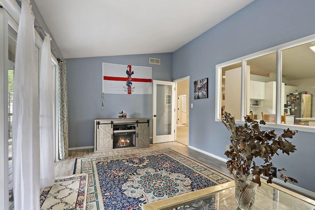 8124 W Imperial Dr, Franklin, WI 53132 - interior space featuring lofted ceiling, wood finished floors, a lit fireplace, baseboards, and french doors
