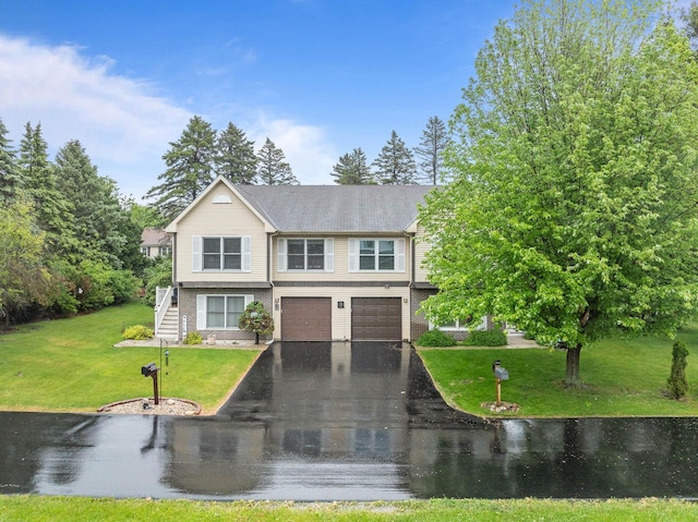 483 W S St Unit A, Lake Geneva, WI 53147 - view of front facade featuring asphalt driveway, stairway, an attached garage, a front yard, and a water view