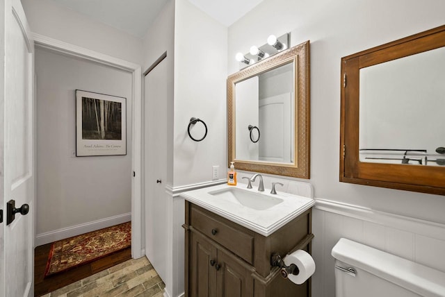 483 W S St Unit A, Lake Geneva, WI 53147 - half bathroom featuring vanity, toilet, wood finished floors, and a wainscoted wall