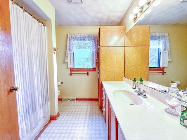 1965 Rockfence Ln, Beloit, WI 53511 - bathroom with tile patterned floors, healthy amount of natural light, vanity, and toilet