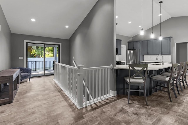 9435 402nd Ave, Genoa City, WI 53128 - kitchen with freestanding refrigerator, light countertops, high vaulted ceiling, a kitchen bar, and light wood-style flooring