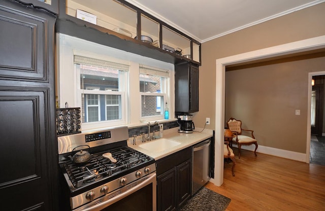 3524 Washington Ave, Racine, WI 53402 - kitchen with appliances with stainless steel finishes, a sink, ornamental molding, light wood finished floors, and dark cabinets