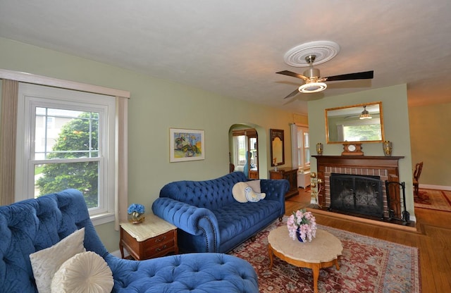3524 Washington Ave, Racine, WI 53402 - living room featuring arched walkways, wood finished floors, ceiling fan, a brick fireplace, and baseboards