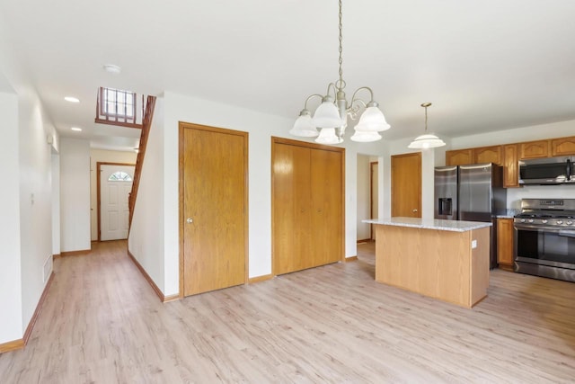 24434 88th St, Salem, WI 53168 - kitchen featuring appliances with stainless steel finishes, light wood-style flooring, a kitchen island, a chandelier, and brown cabinetry