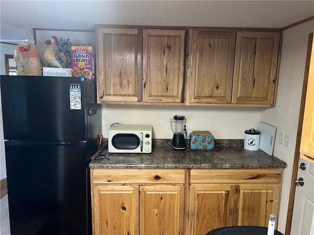 415 S River, Spooner, WI 54801 - kitchen with freestanding refrigerator, dark countertops, and brown cabinets