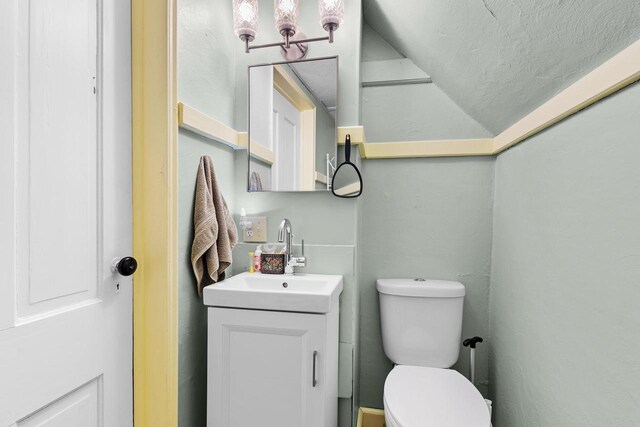 254 Mill St, Algoma, WI 54201 - bathroom featuring vanity, vaulted ceiling, toilet, and a textured ceiling