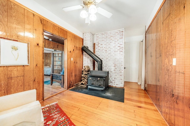 W6641 N Lakeshore Dr, Elkhorn, WI 53121 - living area featuring a wood stove, light wood-type flooring, a ceiling fan, and wood walls