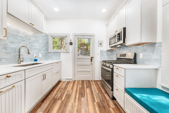 W6641 N Lakeshore Dr, Elkhorn, WI 53121 - kitchen with appliances with stainless steel finishes, a sink, light wood-type flooring, and decorative backsplash