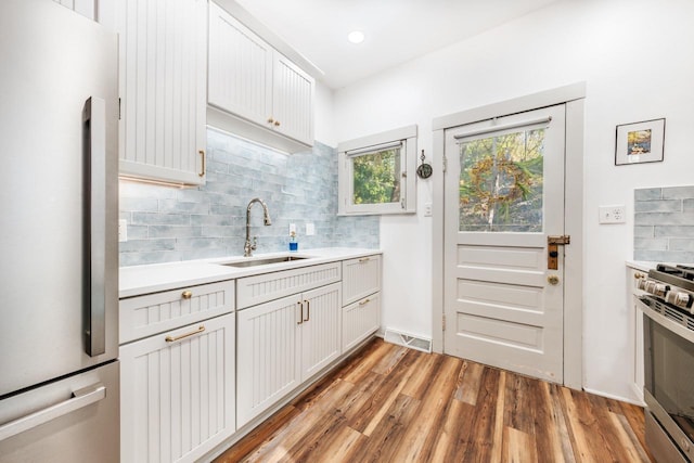 W6641 N Lakeshore Dr, Elkhorn, WI 53121 - kitchen featuring appliances with stainless steel finishes, a sink, light wood-type flooring, decorative backsplash, and light countertops