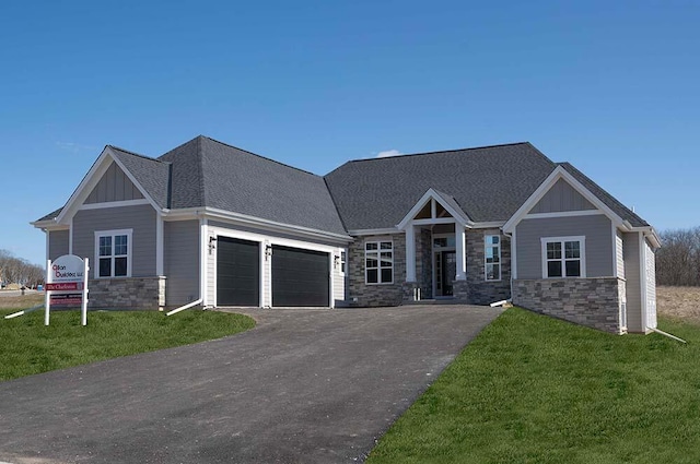 W214N6684 Fairview Dr, Menomonee Falls, WI 53051 - craftsman-style house with stone siding, an attached garage, board and batten siding, driveway, and a front yard