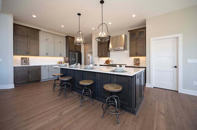 W214N6684 Fairview Dr, Menomonee Falls, WI 53051 - kitchen featuring wall chimney range hood, light countertops, dark wood finished floors, a breakfast bar area, and recessed lighting