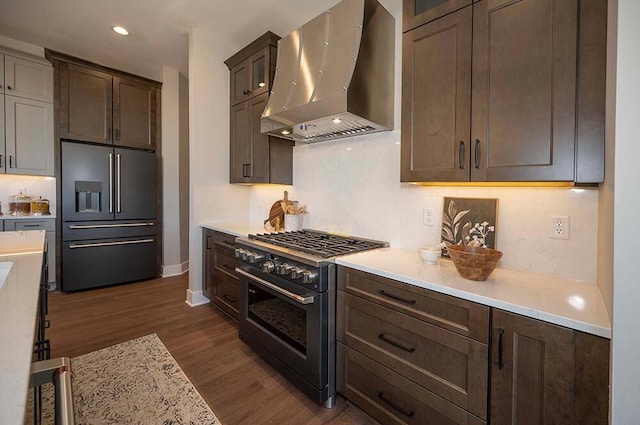 W214N6684 Fairview Dr, Menomonee Falls, WI 53051 - kitchen featuring wall chimney exhaust hood, high quality appliances, light countertops, dark wood-style floors, and recessed lighting