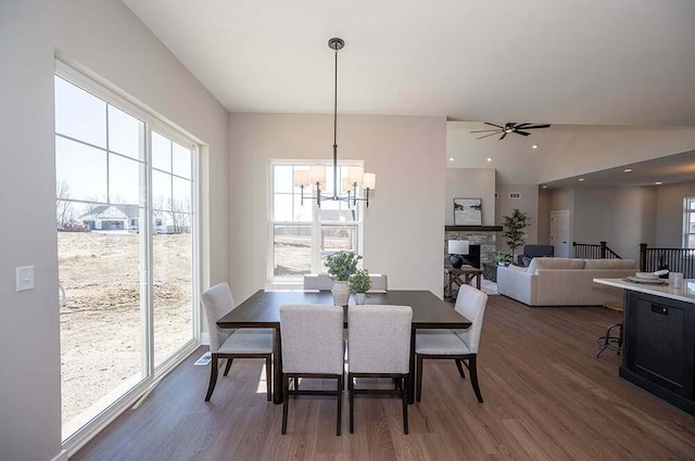 W214N6684 Fairview Dr, Menomonee Falls, WI 53051 - dining space with wood finished floors, a chandelier, a stone fireplace, and a ceiling fan