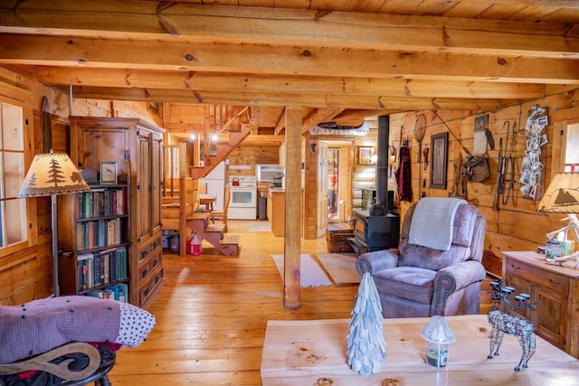 N8378 Timber Trl, New Lisbon, WI 53950 - living room featuring a wood stove, wood walls, light wood-style floors, stairway, and wood ceiling with exposed beams