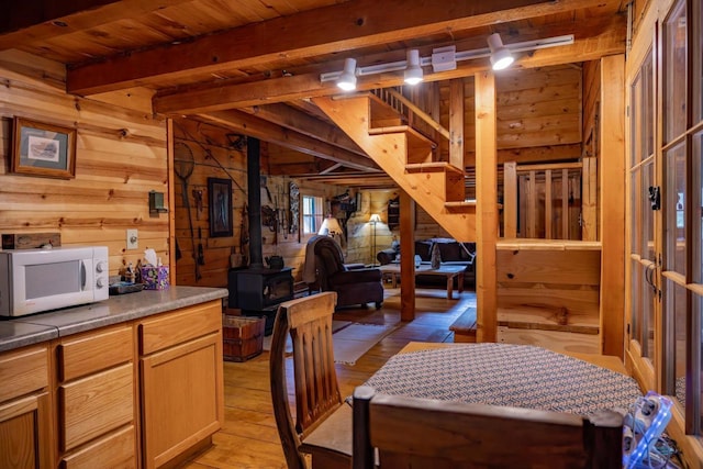 N8378 Timber Trl, New Lisbon, WI 53950 - dining area with a wood stove, wooden walls, stairs, light wood-style flooring, and wooden ceiling with exposed beams