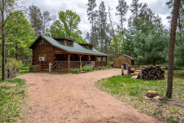 N8378 Timber Trl, New Lisbon, WI 53950 - log home featuring a porch, dirt driveway, an outbuilding, and metal roof