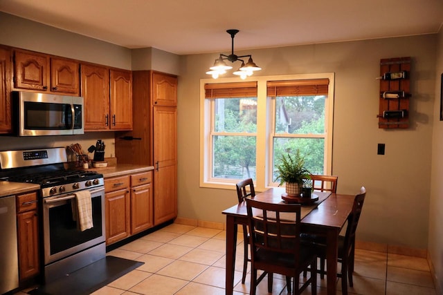 811 Spruce Dr, La Crescent, MN 55947 - kitchen with stainless steel appliances, brown cabinetry, light tile patterned floors, and baseboards