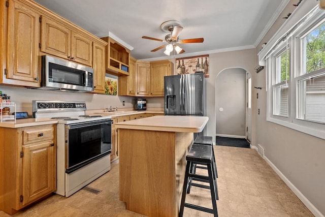 1215 Hastings St, Green Bay, WI 54301 - kitchen featuring appliances with stainless steel finishes, light countertops, arched walkways, a ceiling fan, and ornamental molding