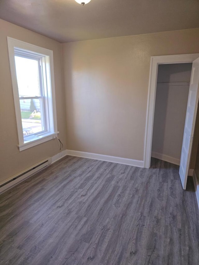 945 N Memorial Dr, Racine, WI 53404 - unfurnished bedroom featuring dark wood finished floors, baseboards, a baseboard heating unit, and a closet