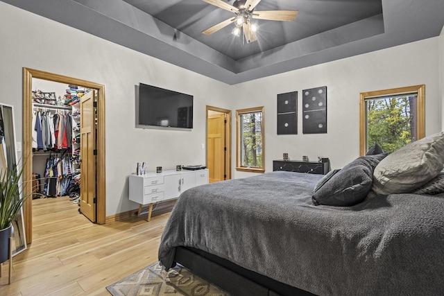 216 Deforest Dr, Kaukauna, WI 54130 - bedroom featuring a tray ceiling, light wood-style floors, a walk in closet, and multiple windows